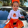 toddler, child, baby, orange_headband, orange_pants, white_shirt, halloween, pumpkin_design, outdoor, car, sunny, trees, smiling, sitting, happy, daylight, headband, pants, baby_clothes, portrait