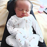 Maisie joined the competition — help win amazing prizes! baby, newborn, sleeping, onesie, white_clothing, floral_pattern, infant, person, lap, blanket, bottle, pink, resting, cute, indoors, soft_lighting, peaceful, cozy, human, portrait