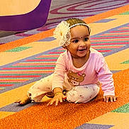 Aarna joined the competition — help win amazing prizes! child, baby, toddler, smiling, headband, flower_headband, pink_clothing, pants, bracelet, carpet, colorful, playful, sitting, portrait, indoors, happy, cheek, eyes, mouth, cute