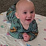 baby, child, smiling, pajamas, blanket, indoor, cute, infant, face, hands, happy, lying_down, expression, clothing, person, toddler, skin, eyes, head, cozy