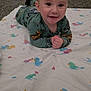 Creed is registered to the contest to win money with this photo: baby, child, smiling, pajamas, blanket, duck_pattern, carpet, indoor, face, hands, lying_down, cute, infant, green_clothing, floor, happy, toddler, portrait, playtime, home