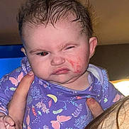 Peyton joined the competition — help win amazing prizes! baby, child, face, expression, grimace, hair, wet_hair, purple_clothing, onesie, butterfly_pattern, hand, person, indoor, portrait, cheek_mark, holding, human, skin, head, cute