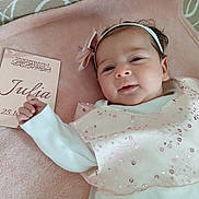 Julia a rejoint le concours — aidez-le/la à gagner de superbes lots ! baby, infant, girl, smile, headband, bow, dress, sequins, blanket, soft_texture, card, name, date, lying_down, portrait, cute, indoors, child, person, happy