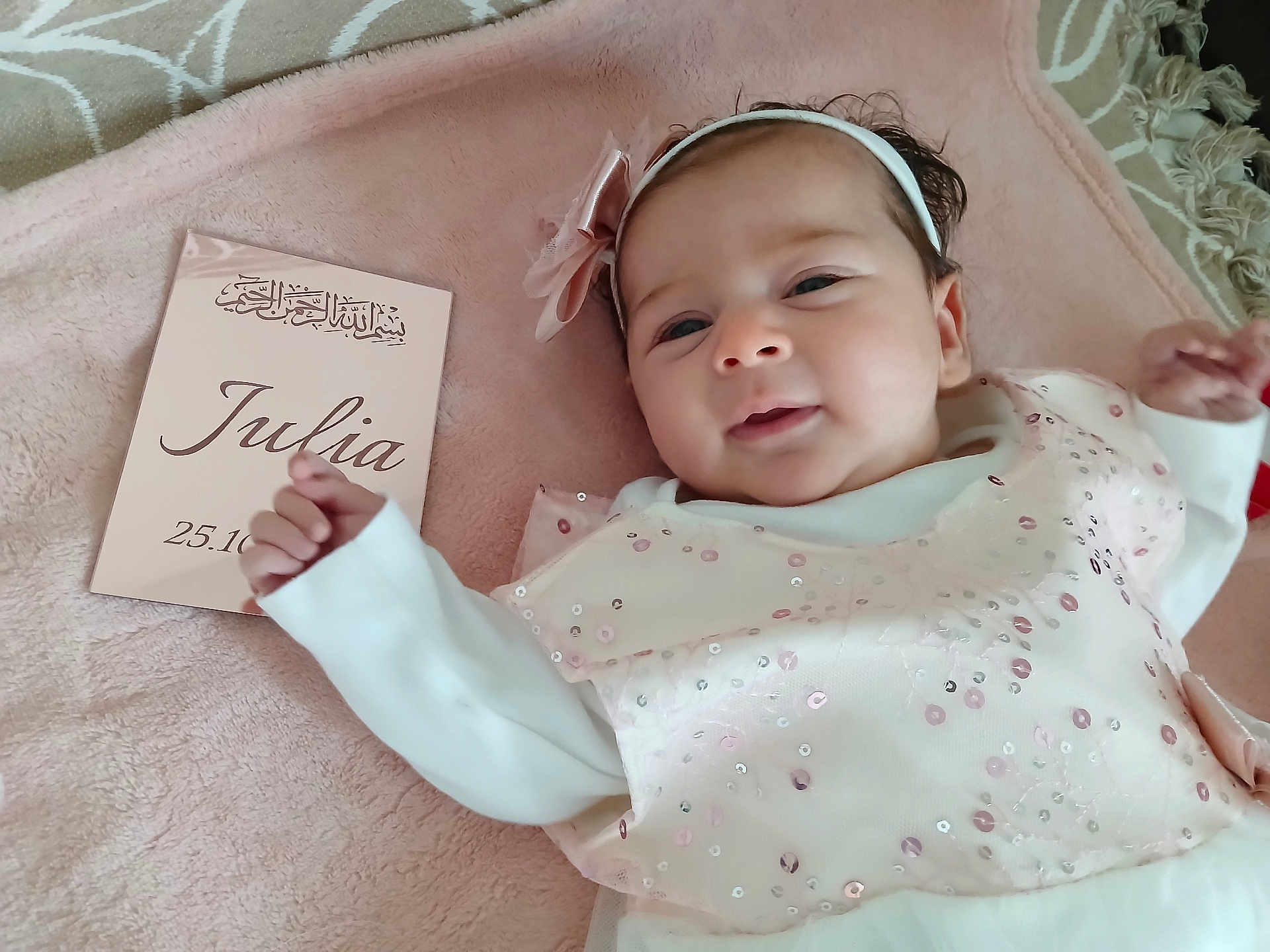 Julia a rejoint le concours — aidez-le/la à gagner de superbes lots ! baby, infant, girl, smile, headband, bow, dress, sequins, blanket, soft_texture, card, name, date, lying_down, portrait, cute, indoors, child, person, happy