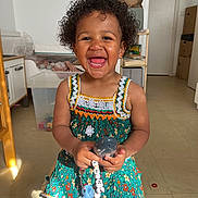 Nejma a rejoint le concours — aidez-le/la à gagner de superbes lots ! box, cabinet, child, curly_hair, cute, dress, floor, furniture, happy, indoor, pacifier, person, playful, portrait, room, shadow, smiling, sunlight, toddler, toy