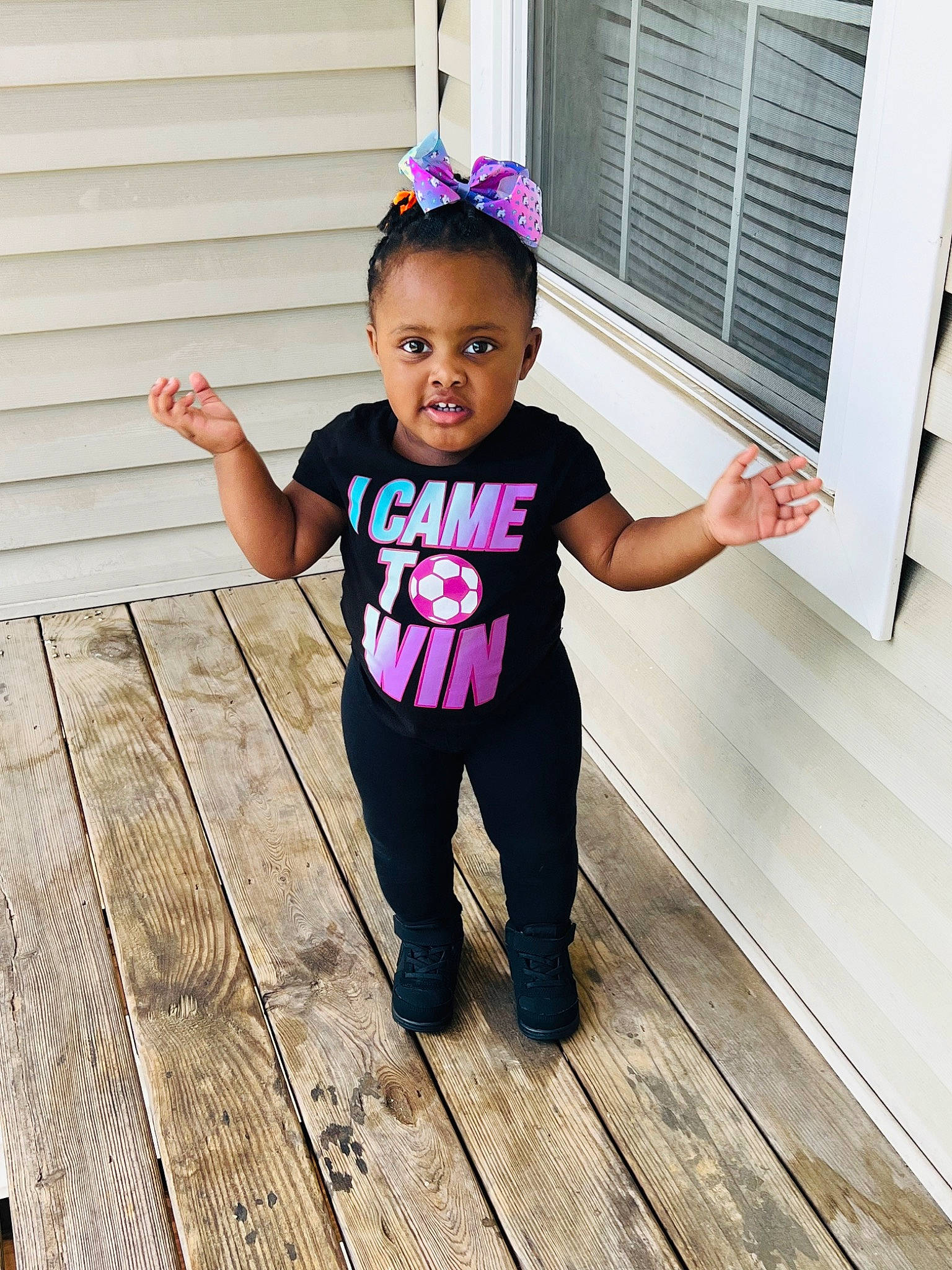Zariah is registered to the contest to win money with this photo: baby_toddler_clothing, child, door, flooring, happy, hardwood, magenta, person, pink, purple, sleeve, standing, sweatpant, t_shirt, toddler, waist, window, window_blind, wood, wood_flooring
