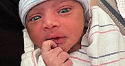 Noel is registered to the contest to win money with this photo: newborn, baby, infant, wrapped, blanket, hat, striped_hat, hospital, person, hand, face, eyes, indoor, carpet, floor, resting, cute, small, cozy, portrait