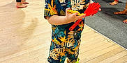 Kevin is registered to the contest to win money with this photo: toddler, child, person, clothing, toy, floor, indoor, party, people, footwear, socks, patterned_clothing, colorful, curly_hair, standing, holding, background, legs, festival, celebration