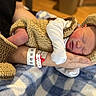 Christopher joined the competition — help win amazing prizes! newborn, baby, sleeping, infant, portrait, cradled, arms, adult, knitted_clothing, blanket, hospital, wristband, peaceful, cozy, indoors, warm_lighting, closed_eyes, face, family, resting