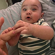 Antonio joined the competition — help win amazing prizes! baby, child, infant, hand, finger, striped_shirt, quilted_blanket, surprised_expression, person, indoors, bed, clothing, skin, face, head, eyes, mouth, furniture, comfort, interaction