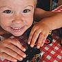 child, smiling, toy, monster_truck, tablecloth, red, white, hands, fingernails, closeup, face, play, happy, indoor, person, cute, expression, childhood, fun, young
