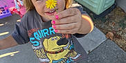Maisie joined the competition — help win amazing prizes! child, flower, yellow_flower, pink_nails, outdoor, sunlight, playing, toy, boots, concrete, smiling, tshirt, blonde_hair, person, sidewalk, fence, hand, happy, nature, daylight
