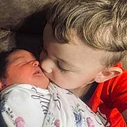 Berkleigh joined the competition — help win amazing prizes! affection, baby, blanket, child, closeup, comfort, couch, face, family, hair, indoor, kiss, love, newborn, portrait, red_shirt, sibling, skin, swaddle, toddler