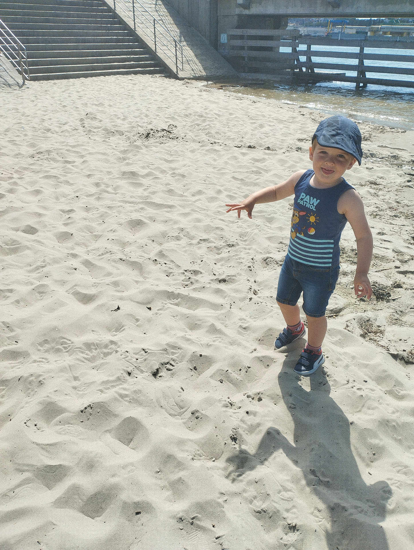 Khyako a rejoint le concours — aidez-le/la à gagner de superbes lots ! child, boy, beach, sand, shadow, water, stairs, cap, tank_top, shorts, footwear, sunlight, outdoor, playful, smiling, casual_clothing, daytime, person, shore, summer