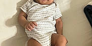 Hezakiah is registered to the contest to win money with this photo: baby, child, smiling, onesie, bed, lying_down, infant, happy, skin, face, person, cute, sleepwear, human, young, indoors, blanket, comfort, resting, toddler