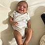 baby, child, smiling, onesie, bed, lying_down, infant, happy, skin, face, person, cute, sleepwear, human, young, indoors, blanket, comfort, resting, toddler