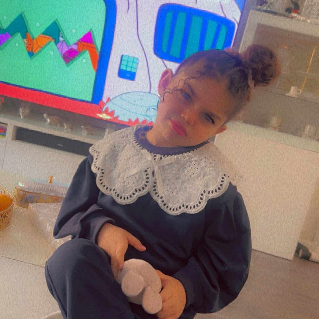 Ayline -Nour a rejoint le concours — aidez-le/la à gagner de superbes lots ! boots, cartoon, child, clothing, cupboard, decor, expression, floor, furniture, hair_bun, home, indoor, lace_collar, plant, plush, relaxed, sitting, table, television, toy