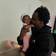 Jreame joined the competition — help win amazing prizes! baby, child, man, smile, kiss, indoor, headband, pink_pants, happy, family, love, affection, holding, person, clothing, furniture, carpet, baby_bed, cozy, casual