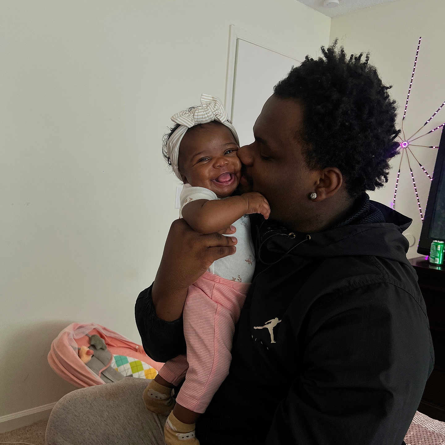 Jreame joined the competition — help win amazing prizes! baby, child, man, smile, kiss, indoor, headband, pink_pants, happy, family, love, affection, holding, person, clothing, furniture, carpet, baby_bed, cozy, casual