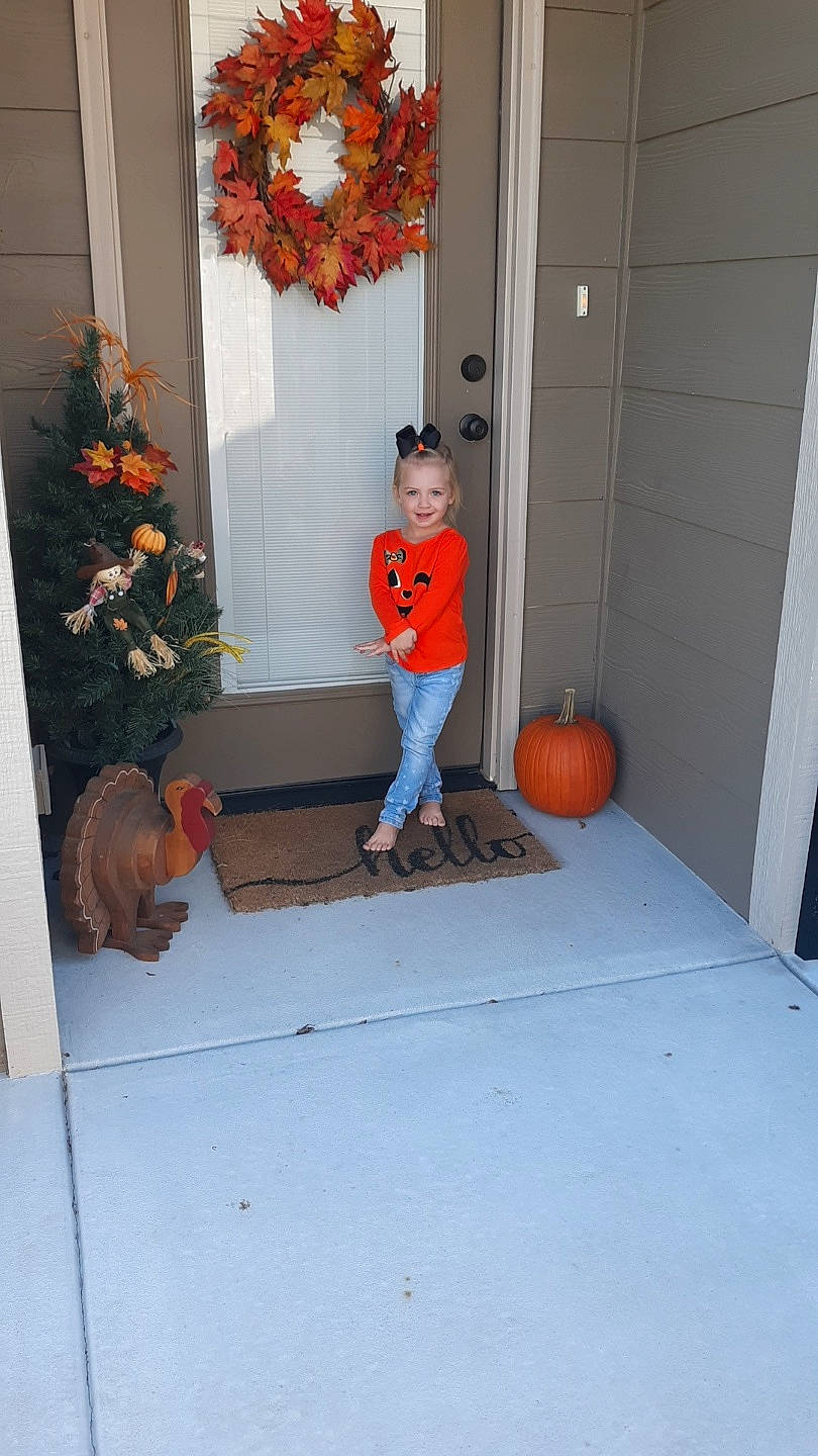 Jojo is registered to the contest to win money with this photo: child, door, fawn, floor, home, house, joy, person, porch, pumpkin, room