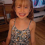 Lya participe au concours pour gagner de l'argent avec cette photo : girl, child, smile, dress, headband, indoor, wooden_floor, wooden_chair, television, people, happy, brown_hair, floral_pattern, person, room, furniture, bracelet, curly_hair, portrait, standing