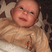 Lya participe au concours pour gagner de l'argent avec cette photo : baby, infant, blanket, clothing, giraffe_embroidery, cushion, face, portrait, smile, eyes, soft_lighting, indoor, cozy, child, young, cute, warm_colors, patterned_background, sleepwear, resting