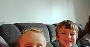 Bellamy joined the competition — help win amazing prizes! boy, casual, child, children, couch, curly_hair, furniture, gray_shirt, happy, indoor, living_room, person, portrait, red_shirt, relaxed, seated, short_hair, smile, toddler, young