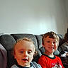 Bellamy joined the competition — help win amazing prizes! child, children, couch, indoor, smile, happy, boy, toddler, seated, casual, curly_hair, short_hair, red_shirt, gray_shirt, living_room, person, furniture, portrait, young, relaxed