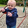 Bellamy is registered to the contest to win money with this photo: child, toddler, outdoor, playground, rope_climbing_structure, jacket, blue_jeans, wood_chips, trees, smiling, playing, person, casual_clothing, daylight, fun, active, reaching, young_child, nature, park