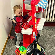 Bellamy joined the competition — help win amazing prizes! child, toy, cash_register, play, indoor, carpet, red, plastic, pretend_play, food, spoon, clothing, person, young_child, home, imagination, shopping, pretend, play_kitchen, curly_hair
