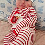 baby, infant, santa_hat, striped_pajamas, red_and_white, blanket, bed, rosy_cheeks, smile, cute, hand, foot, lying_down, cozy, christmas, festive, portrait, hat, face, person
