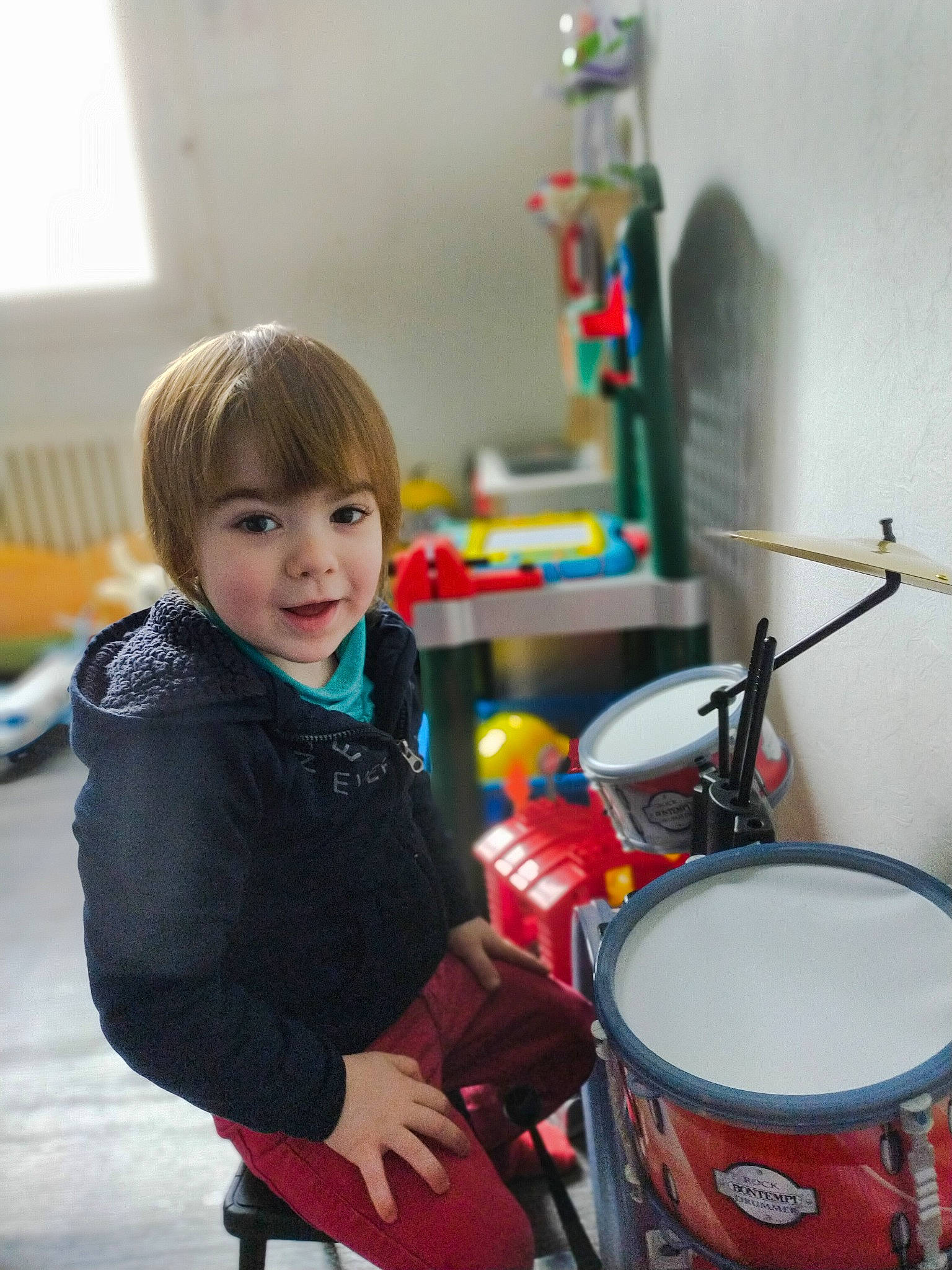 Tyméo participe au concours pour gagner de l'argent avec cette photo : chair, child, conga, drum, drum_stick, drumhead, drums, event, hand_drum, happy, idiophone, membranophone, musical_instrument, musician, percussion, person, room, sitting, smile, toddler