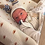 élio a rejoint le concours — aidez-le/la à gagner de superbes lots ! newborn, baby, infant, hat, clothing, blanket, cushion, pattern, sun_motif, bed, resting, indoor, young_child, portrait, face, cute, soft, warm, sleeping_area, cozy