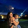 Waylon is registered to the contest to win money with this photo: baby, building, casual_clothing, child, darkness, face, grass, happy, holding, jeans, light_beam, moon, night, outdoor, person, portrait, short_sleeve, sky, smile, woman