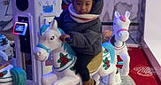 Hilona participe au concours pour gagner de l'argent avec cette photo : amusement_ride, boots, carousel, child, coat, decorative, face, family_fun, indoor, kid, led_lights, merry_go_round, person_peeking, platform, play, portrait, red_carpet, scarf, smile, toy_horse