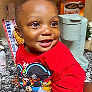 Tierre Aka Fatman is registered to the contest to win money with this photo: toddler, child, smiling, red_shirt, mickey_mouse, kitchen, countertop, keurig, coffee_box, happy, portrait, indoor, face, person, cute, baby, short_hair, bright_eyes, expression, clothing