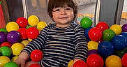 Vincent joined the competition — help win amazing prizes! ball_pit, balls, bright_colors, casual_clothing, child, colorful, face, fun, happy, indoor, leisure, person, play, playpen, seated, smiling, striped_shirt, toddler, toy, young_child