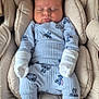 baby, sleeping, stroller, pajamas, blue_clothing, cozy, indoor, child, infant, cute, soft, cushioned, footwear, face, head, peaceful, person, resting, young, adorable
