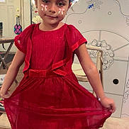 Mariana is registered to the contest to win money with this photo: child, girl, red_dress, indoor, playful, face_stickers, pink_bows, wooden_floor, chair, decorated_house, window, curtains, smiling, person, home, floor, furniture, cute, posing, young