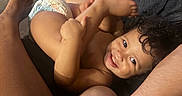Alexia is registered to the contest to win money with this photo: toddler, child, smiling, curly_hair, face, eyes, teeth, diaper, baby, cuddling, family, adult, arms, legs, feet, couch, indoor, home, portrait, playful