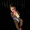 baby, bottle, diaper, drinking, infant, child, milk, cute, face, feet, hands, skin, dark_background, lighting, portrait, young_child, alone, indoor, candid, expression