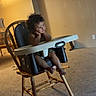 toddler, child, baby, high_chair, sitting, curly_hair, facial_expression, hands_on_cheeks, indoor, home, dining_room, chair, furniture, carpet, warm_lighting, portrait, full_body, graco, family_scene, cable