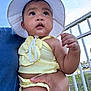 Arleth Lopez joined the competition — help win amazing prizes! baby, child, hat, yellow_clothing, sunhat, outdoor, blue_sky, person, hand, curious, infant, summer, daylight, railing, nature, portrait, holding, cute, skin, expression