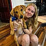 woman, dog, indoor, wooden_floor, smiling, blonde_hair, bandana, pet, animal, human, flooring, casual, holding, cute, friendly, home, portrait, happy, kneeling, domestic