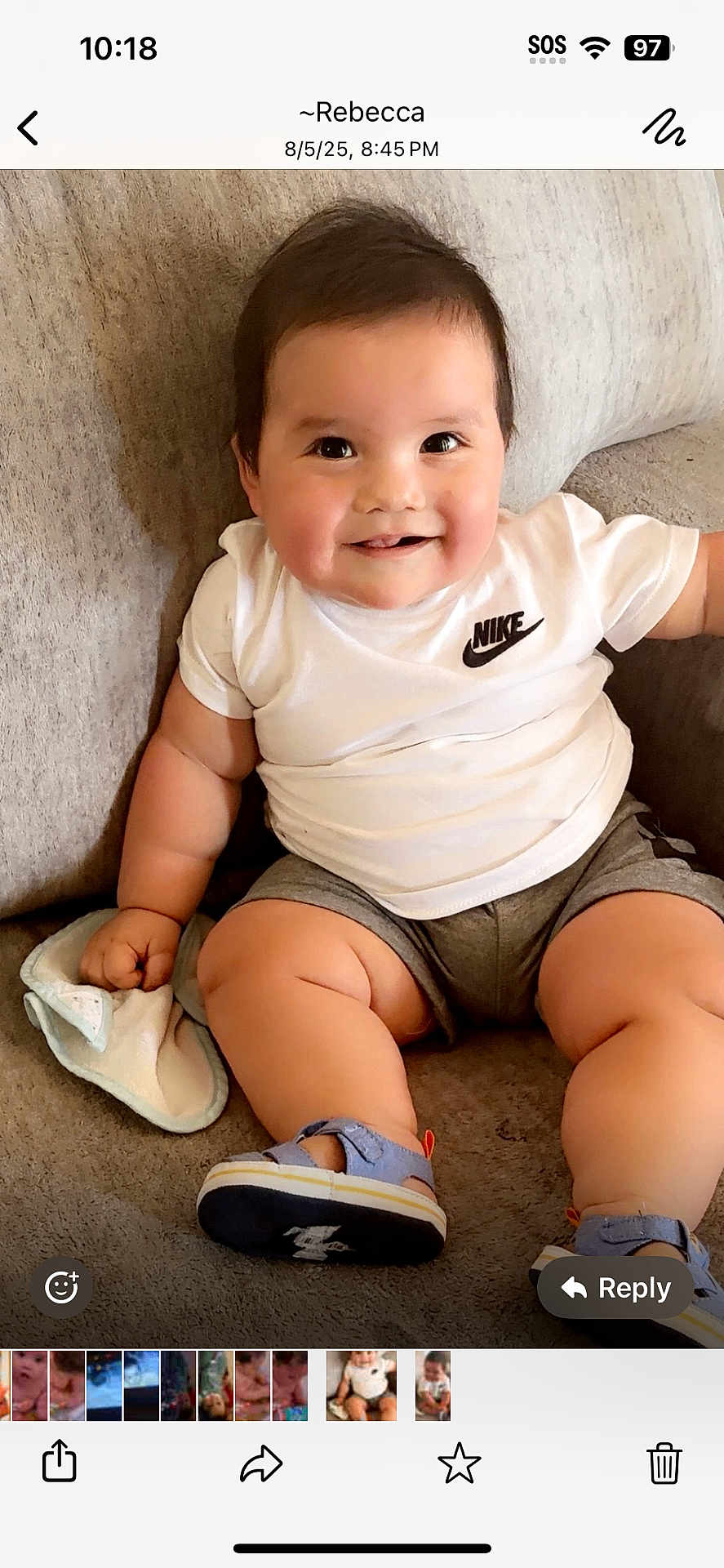 Jeremiah joined the competition — help win amazing prizes! baby, child, smiling, sitting, white_shirt, nike_logo, gray_shorts, blue_sandals, couch, soft_furniture, indoors, cute, happy, chubby, infant, holding_cloth, short_hair, skin, casual_clothing, portrait