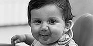 Soan participe au concours pour gagner de l'argent avec cette photo : baby, bib, black_and_white, child, clothing, cute, expression, face, food, hair, high_chair, indoor, messy, person, playful, portrait, seat, smile, toddler, young