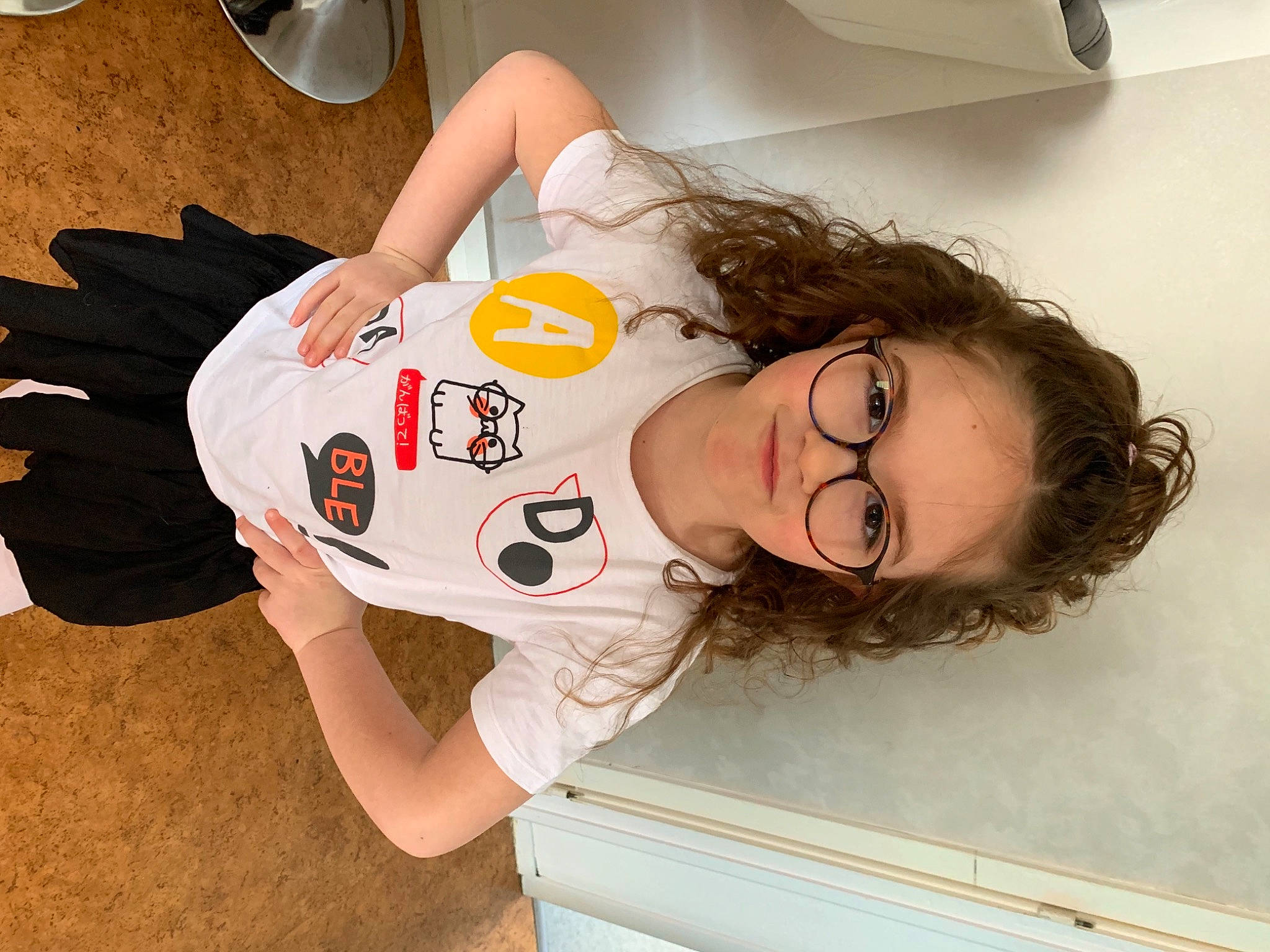 Emma a rejoint le concours — aidez-le/la à gagner de superbes lots ! bangs, black_hair, carmine, child, comfort, elbow, eyelash, eyewear, fun, happy, human_leg, neck, person, room, shoulder, sleeve, t_shirt, thigh, top