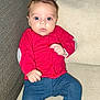 baby, blue_pants, child, comfortable, couch, cozy, cushion, cute, expression, face, indoor, infant, looking, person, portrait, red_sweater, sitting, small, socks, young