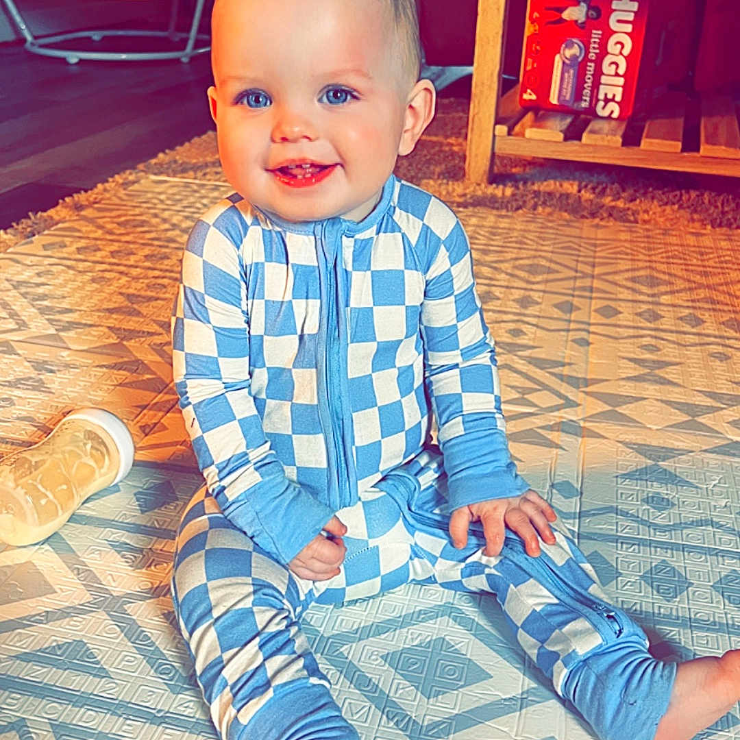 Kaden is registered to the contest to win money with this photo: architecture, baby, building, clothing, face, furniture, happy, head, indoors, livingroom, machine, pajamas, pants, person, photography, portrait, room, sitting, wheel, wood