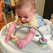 Spencer joined the competition — help win amazing prizes! baby, infant, child, walker, toy, rings, hands, face, blanket, indoor, person, curious, floor, wooden_floor, clothing, adult, background, play, home, furniture